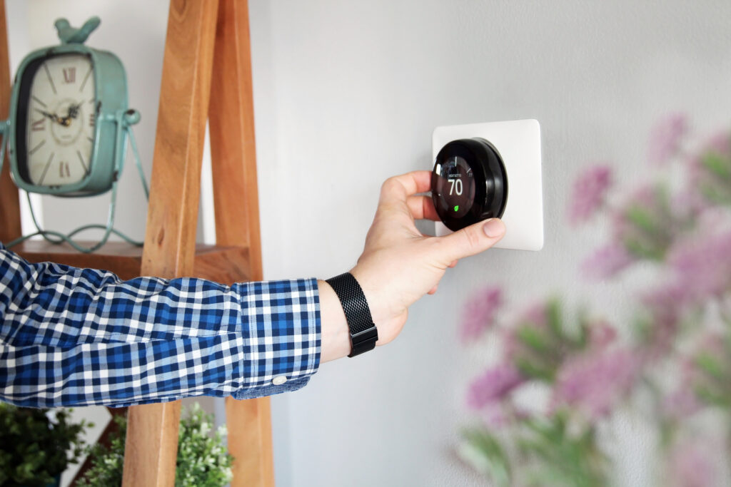 Person adjusting the temperature on a thermostat in the living room