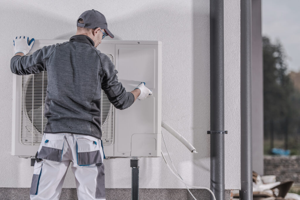 A technician installing an outdoor heat pump unit