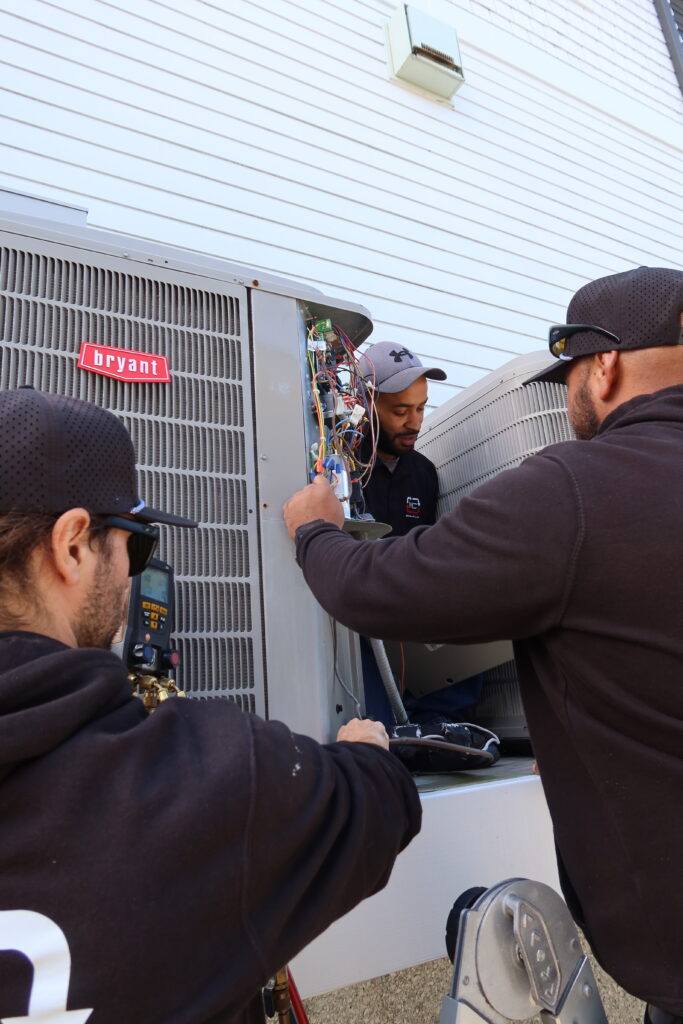 HVAC technicians working on an AC unit