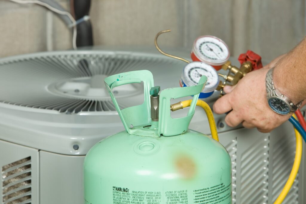 Green Freon r22 tank next to technician using gauge